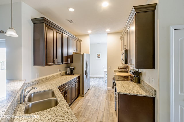 kitchen featuring a sink, appliances with stainless steel finishes, dark brown cabinetry, and visible vents