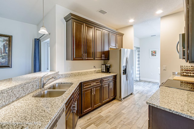 kitchen featuring dark brown cabinetry, appliances with stainless steel finishes, a sink, and light stone counters