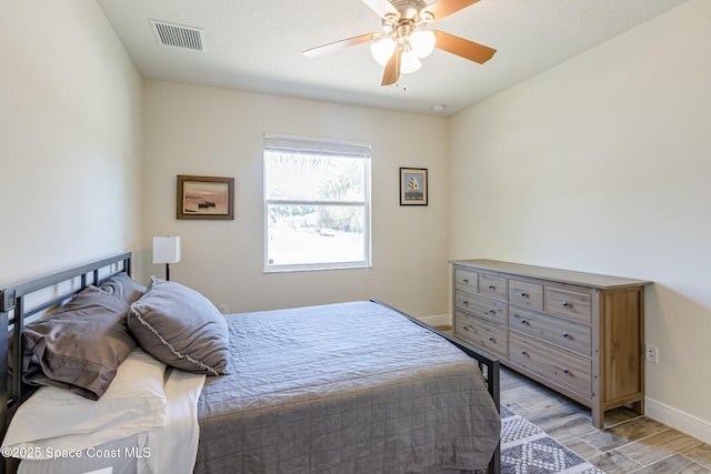 bedroom featuring baseboards, ceiling fan, light wood-style flooring, and visible vents