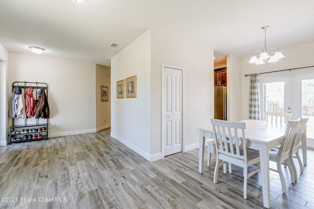 dining space with french doors, visible vents, light wood-type flooring, baseboards, and a chandelier