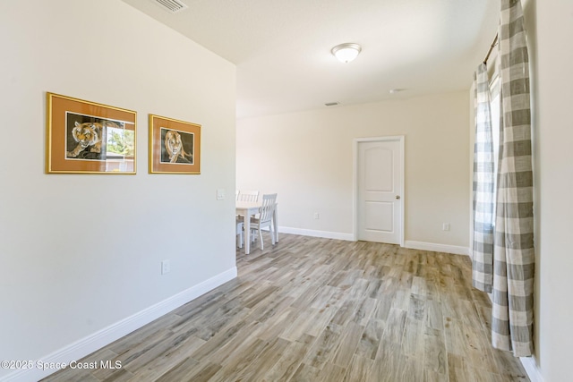 unfurnished room with baseboards and light wood finished floors