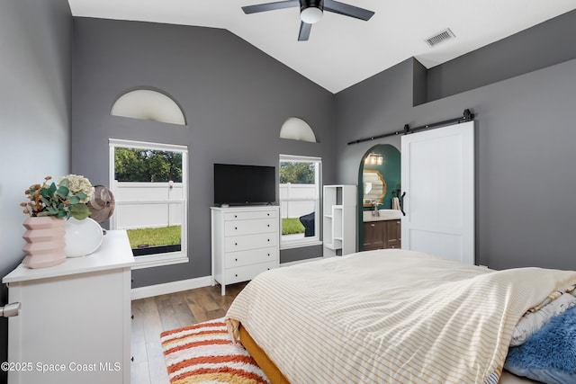2801 Saint James Ln, Melbourne, FL 32935 - bedroom featuring a barn door, wood finished floors, high vaulted ceiling, and ceiling fan