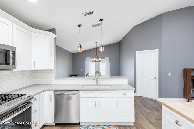 2801 Saint James Ln, Melbourne, FL 32935 - kitchen with appliances with stainless steel finishes, a sink, vaulted ceiling, backsplash, and a peninsula