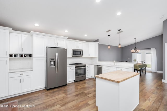 2801 Saint James Ln, Melbourne, FL 32935 - kitchen with stainless steel appliances, a sink, decorative backsplash, vaulted ceiling, and pendant lighting