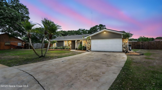 ranch-style house with a garage, fence, a yard, and concrete driveway