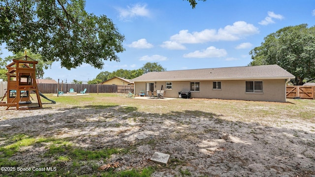 back of property featuring a playground, stucco siding, a fenced backyard, and a patio area