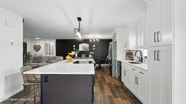 kitchen featuring a sink, light countertops, an island with sink, stainless steel appliances, and visible vents