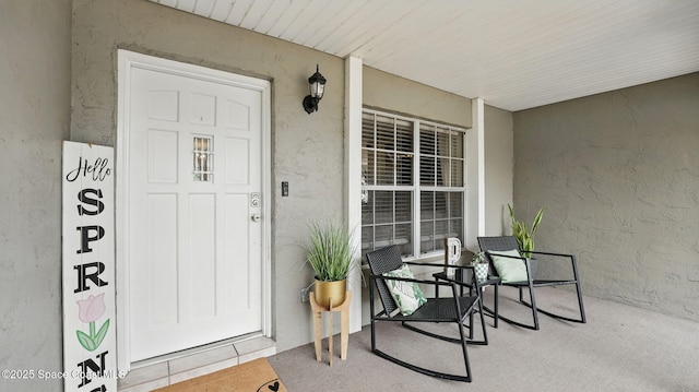 entrance to property with covered porch and stucco siding
