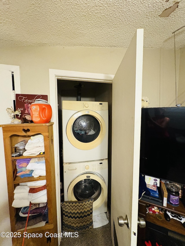 clothes washing area with a textured ceiling, stacked washer / drying machine, and laundry area