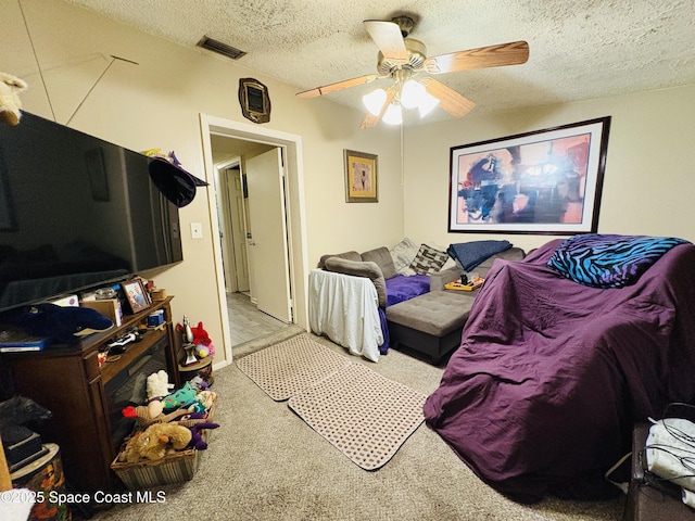 bedroom featuring a ceiling fan, a textured ceiling, visible vents, and carpet