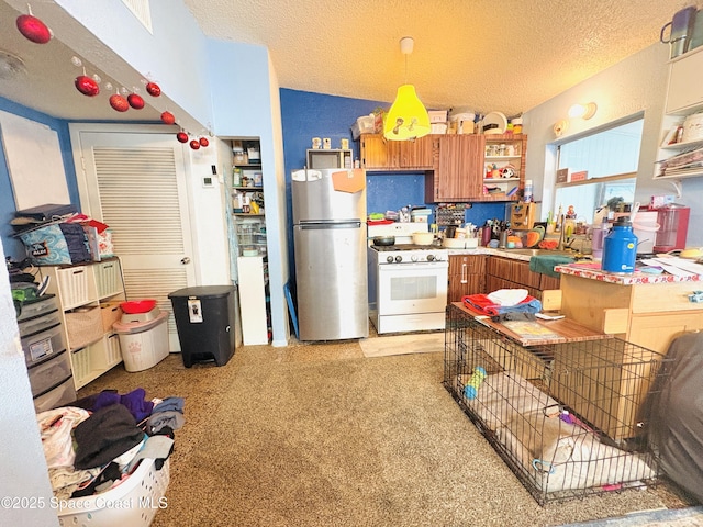 kitchen featuring open shelves, brown cabinets, a sink, white gas range oven, and freestanding refrigerator