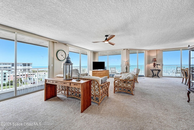carpeted living room featuring ceiling fan, a healthy amount of sunlight, and expansive windows