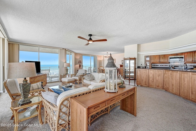 living room featuring ceiling fan, light carpet, and a textured ceiling