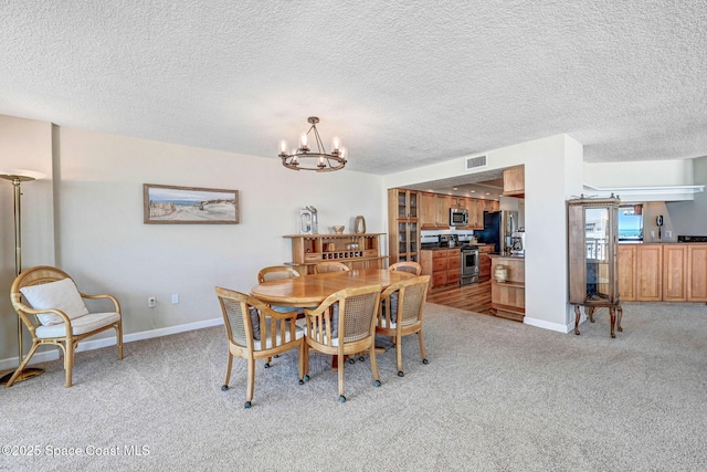dining space featuring light colored carpet, a textured ceiling, a chandelier, and visible vents