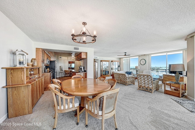 dining space featuring a healthy amount of sunlight, a textured ceiling, and light colored carpet
