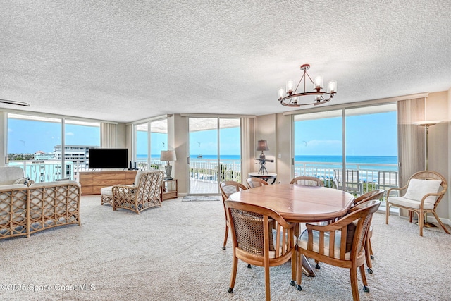 carpeted dining room with a textured ceiling, a notable chandelier, and expansive windows