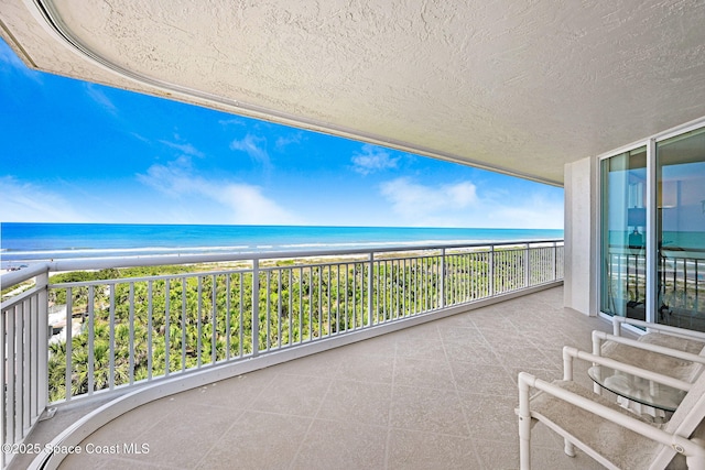 balcony featuring a water view and a view of the beach