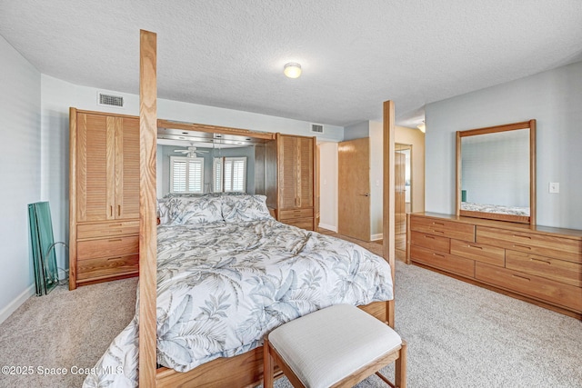 carpeted bedroom featuring a textured ceiling, visible vents, and baseboards