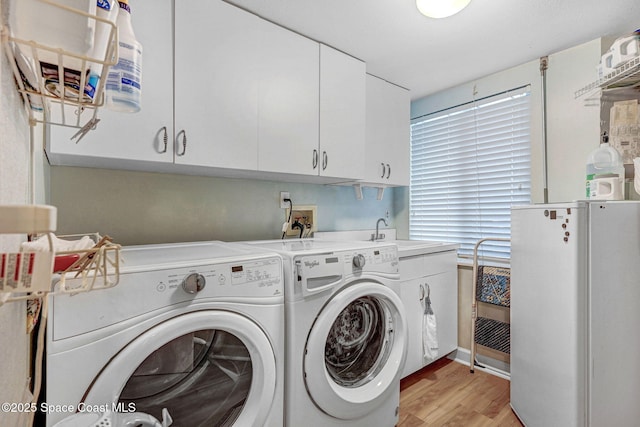 laundry room with a sink, light wood-type flooring, independent washer and dryer, and cabinet space