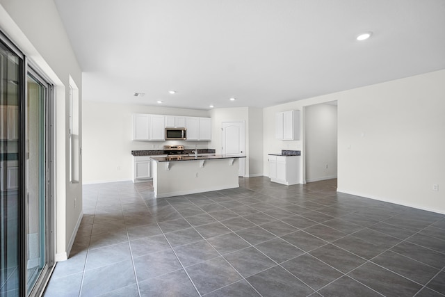 kitchen with white cabinets, dark countertops, stainless steel appliances, recessed lighting, and dark tile patterned floors
