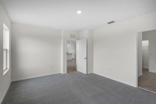 unfurnished bedroom with carpet floors, baseboards, and visible vents