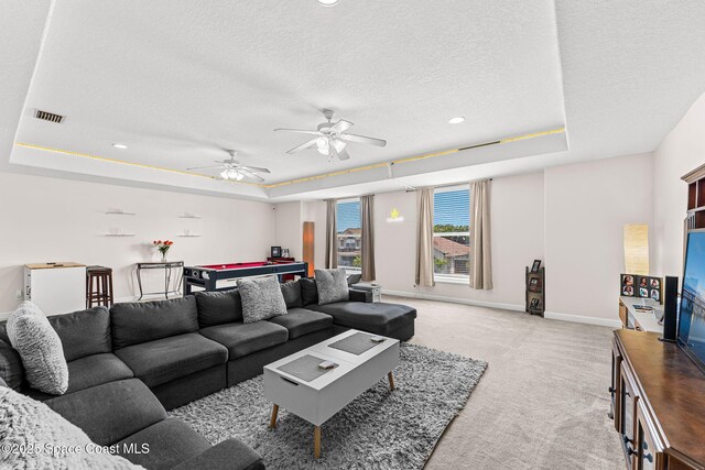 3502 Tipperary Dr, Merritt Island, FL 32953 - living room featuring a raised ceiling, a textured ceiling, light colored carpet, baseboards, and ceiling fan