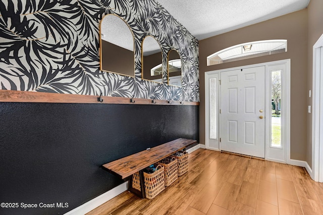 foyer featuring baseboards, a textured ceiling, and wood finished floors