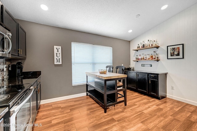 interior space featuring baseboards, a dry bar, and light wood-style flooring