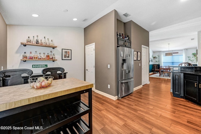 kitchen featuring stainless steel fridge, light wood finished floors, recessed lighting, baseboards, and visible vents