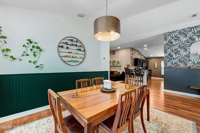 dining room with visible vents, wood finished floors, and a wainscoted wall