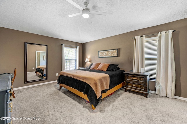 bedroom with baseboards, ceiling fan, light carpet, and a textured ceiling