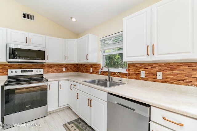 1435 Xavier Ave SE, Palm Bay, FL 32909 - kitchen with appliances with stainless steel finishes, a sink, visible vents, white cabinetry, and vaulted ceiling