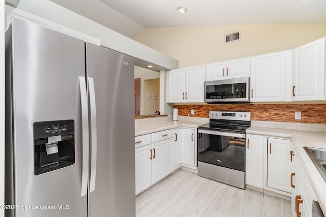 1435 Xavier Ave SE, Palm Bay, FL 32909 - kitchen with visible vents, decorative backsplash, lofted ceiling, white cabinets, and appliances with stainless steel finishes