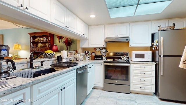 kitchen featuring appliances with stainless steel finishes, under cabinet range hood, light stone countertops, a sink, and recessed lighting