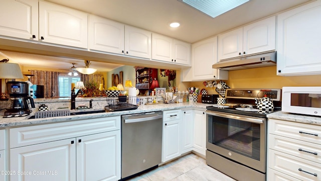 kitchen featuring stainless steel appliances, under cabinet range hood, light tile patterned flooring, a sink, and light stone counters