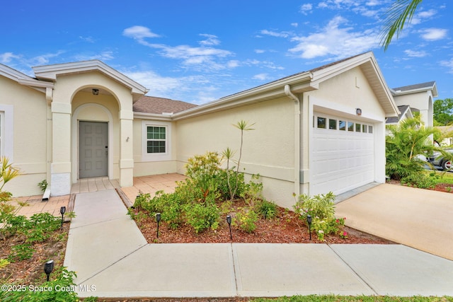 view of front of home with concrete driveway, stucco siding, and a garage