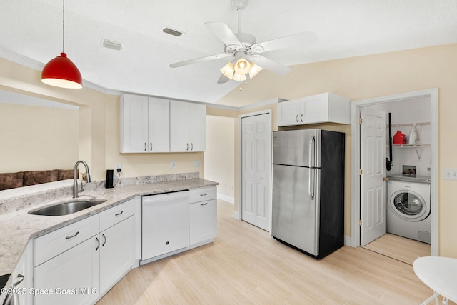 kitchen featuring a sink, washer / dryer, freestanding refrigerator, visible vents, and white dishwasher