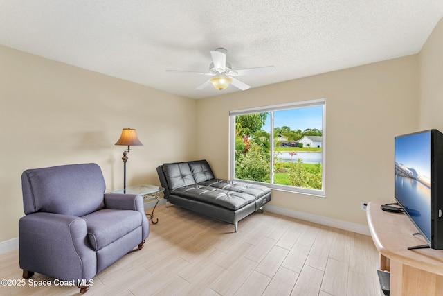 sitting room featuring light wood-style flooring, baseboards, and a ceiling fan