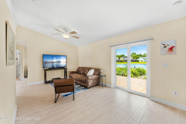 living area featuring baseboards, light wood-type flooring, ceiling fan, and vaulted ceiling