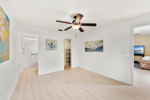 interior space with a ceiling fan, light wood-style floors, visible vents, and baseboards