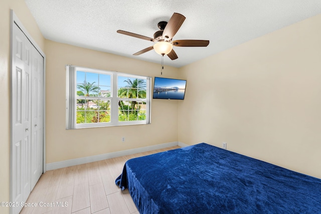 bedroom with baseboards, a closet, ceiling fan, and a textured ceiling