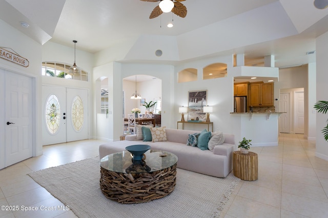 living area featuring a ceiling fan, recessed lighting, light tile patterned floors, a towering ceiling, and arched walkways