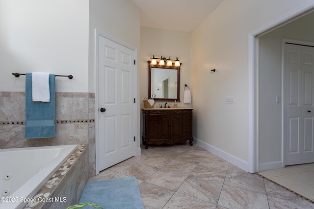 full bathroom with a tub with jets, baseboards, and vanity