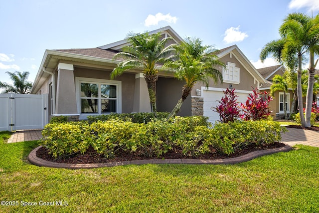 view of front of property featuring an attached garage, a gate, stucco siding, and a front yard