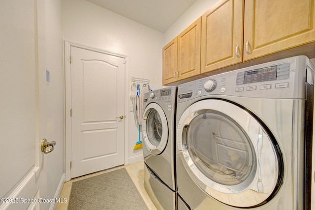 laundry room featuring light tile patterned floors, separate washer and dryer, baseboards, and cabinet space
