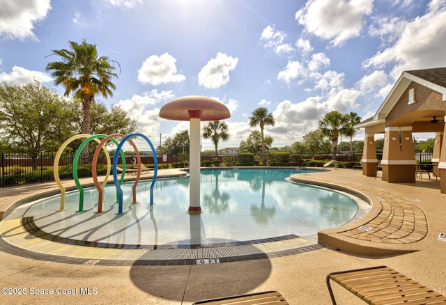 community pool featuring fence, a patio, and a water play area