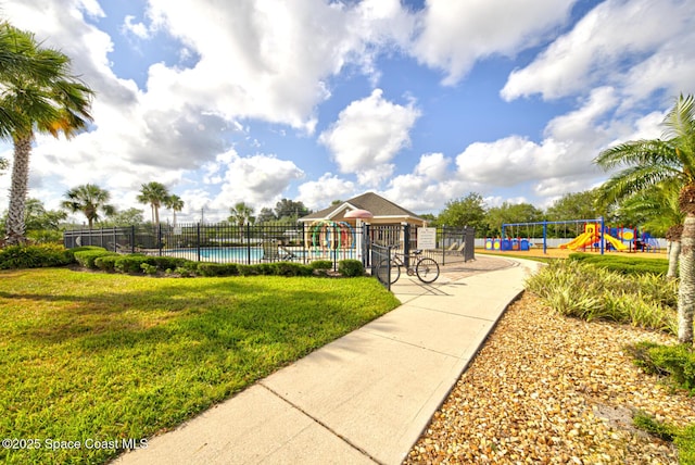 view of home's community featuring a yard, a swimming pool, fence, and playground community