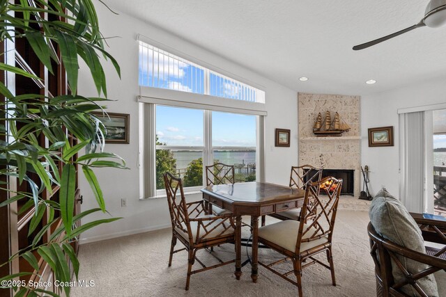 1495 Newfound Harbor Dr, Merritt Island, FL 32952 - carpeted dining room with baseboards, a ceiling fan, a healthy amount of sunlight, and a large fireplace