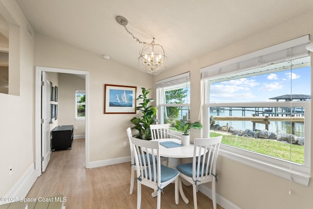 1495 Newfound Harbor Dr, Merritt Island, FL 32952 - dining space featuring vaulted ceiling, baseboards, a chandelier, a water view, and light wood-style flooring