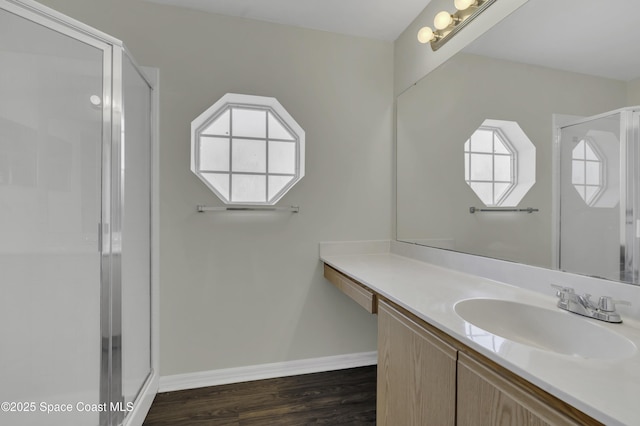 full bathroom featuring baseboards, vanity, a stall shower, and wood finished floors